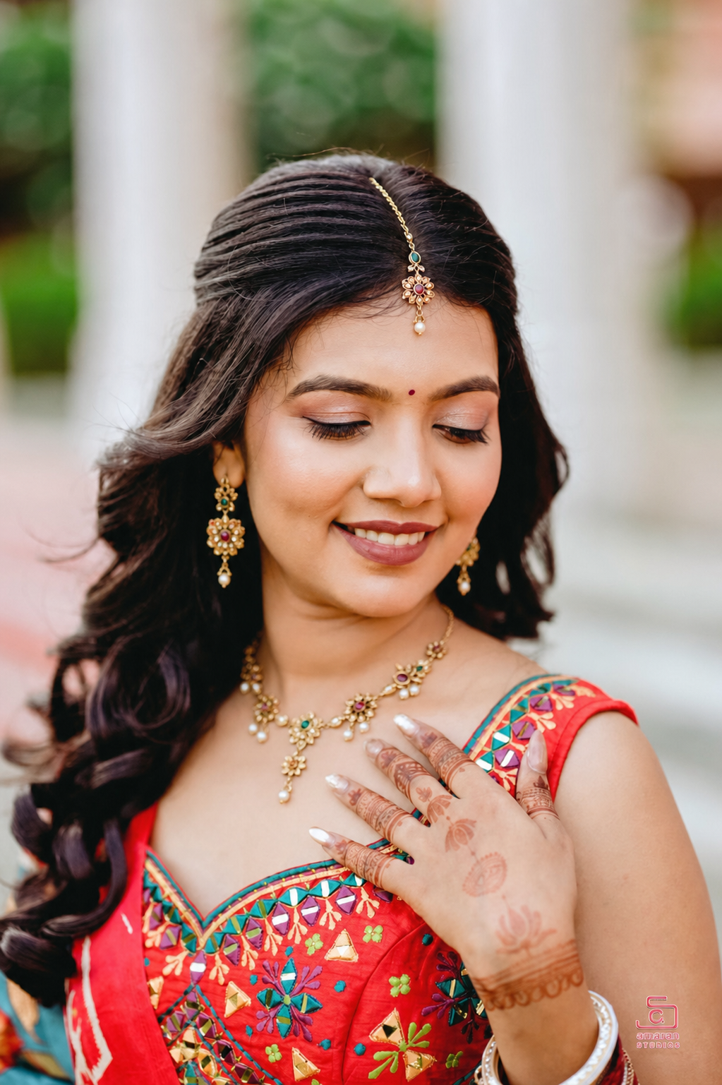 Mrs. Eti smiling in a vibrant traditional outfit with gold jewellery