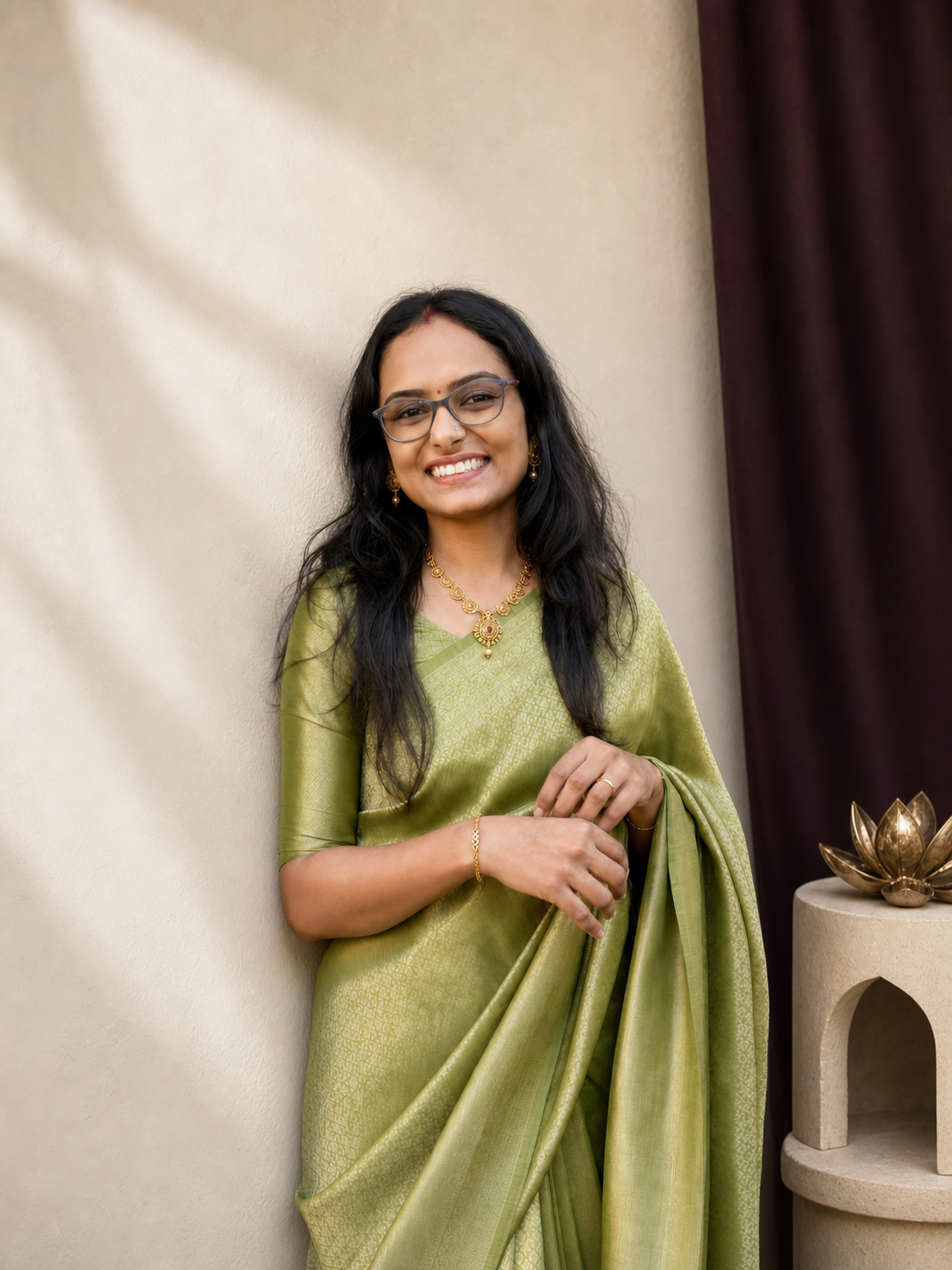 Mrs. Mintu smiling in a green saree and wearing gold jewellery